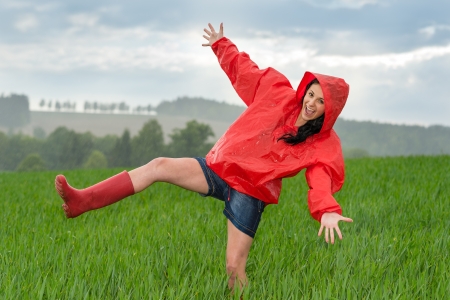 Playful teenage girl dancing in the rain on a field Playful teenage girl dancing in the rain on a field