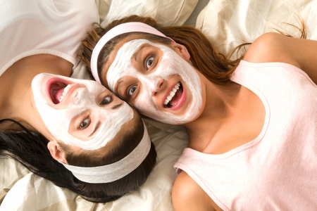 Serene girls lying on bed wearing cosmetic mask and laughingの写真素材
