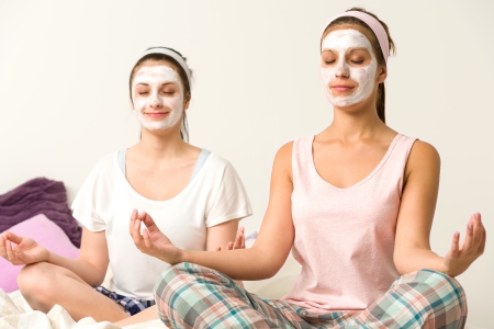 Meditating women sitting cross-legged  wearing white facial maskの写真素材