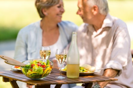 Cheerful senior citizens dating and eating outdoorsの写真素材