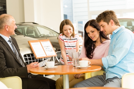 Young couple reading contract in car dealershipの写真素材