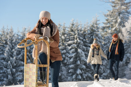 Young woman sunny winter lean against wooden sledge snow