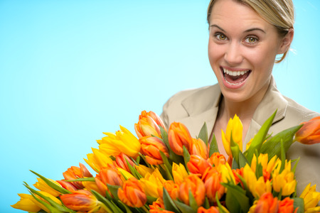 Cheerful woman with bunch of orange yellow spring tulipsの写真素材