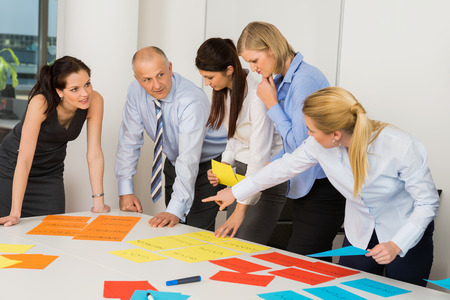 Business team discussing multicolored labels in boardroom meetingの写真素材