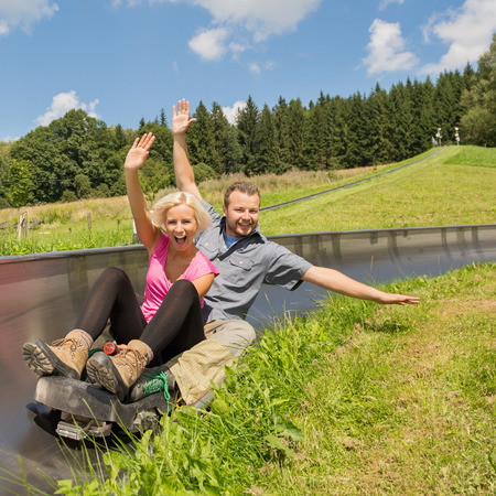 Portrait of young couple enjoying summer sledge rideの写真素材