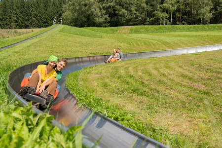 Smiling young couples enjoying summer sledge rideの写真素材