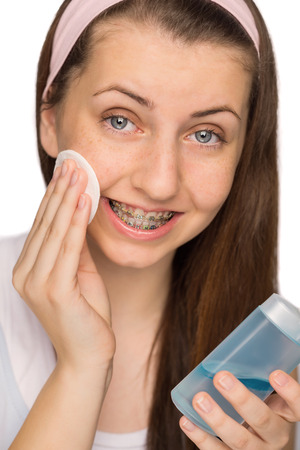 Girl with braces using makeup removal on white backgroundの写真素材