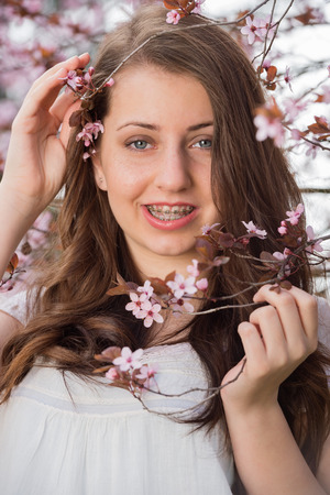 Teenage romantic girl with braces holding blossoming tree branch springの写真素材