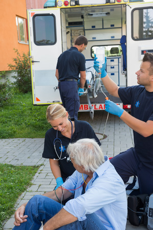 Emergency team treating injured senior patient sitting on streetの写真素材