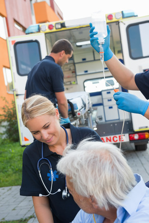 Paramedical team helping injured elderly patient on streetの写真素材
