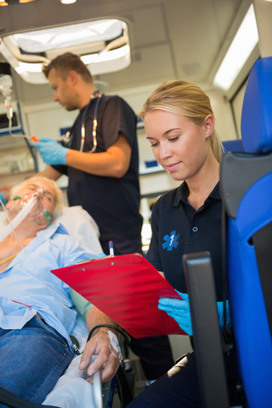Paramedic assisting injured senior patient on stretcher in ambulanceの写真素材