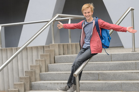 Playful teenage student sliding down railing on school stairwayの写真素材