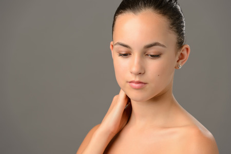 Beauty portrait teenage girl soft skin care looking down gray backgroundの写真素材