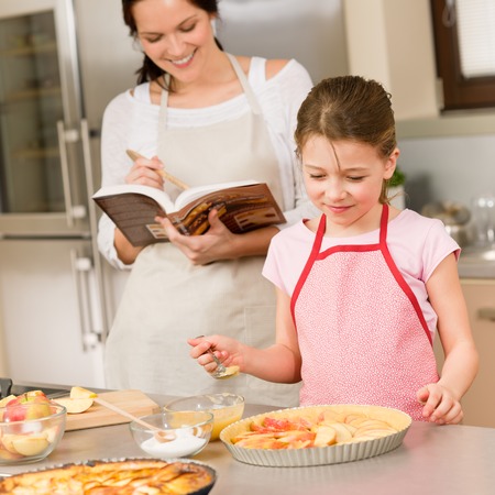 Mother and daughter making apple pie follow recipe from cookbookの写真素材