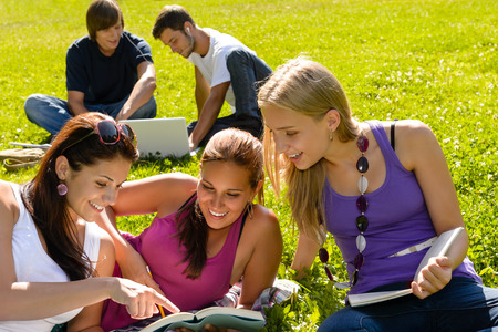 Teens studying in park reading book students happy campus researchの写真素材