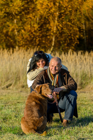 Cheerful couple with retriever dog in autumn countryside sunsetの写真素材