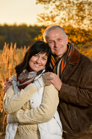 Romantic couple embracing in autumn park backlit by sunsetの写真素材