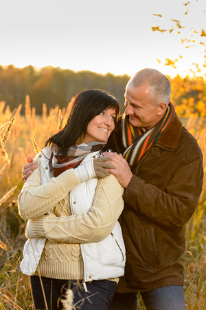 Couple in love hugging sunset autumn countryside looking each otherの写真素材