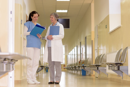 Two female doctors standing in empty hospital corridorの写真素材