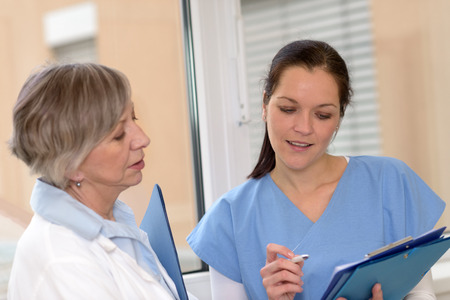 Two female doctors in hospital looking at patient filesの写真素材