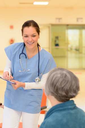 Smiling young female doctor in hospital talking to senior patientの写真素材