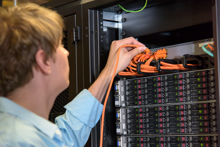 IT specialist patching network wire in rack ful of server hardwareの写真素材