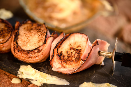 Skewer of grilled scallops wrapped in ham with white wine sauceの写真素材