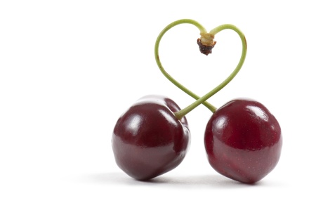 pair of cherries with heart-shaped stem, on white backgroundの写真素材