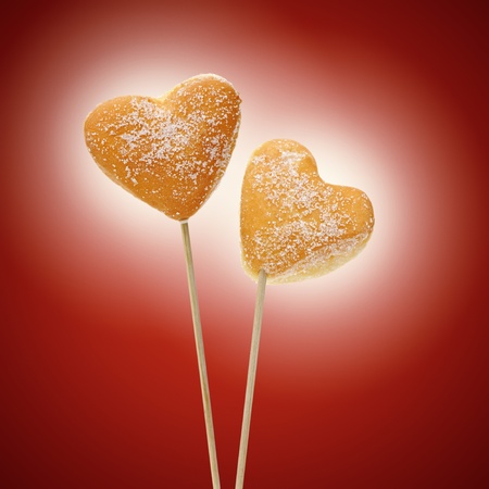 donuts heart-shaped inserted on sticks, on red backgroundの写真素材