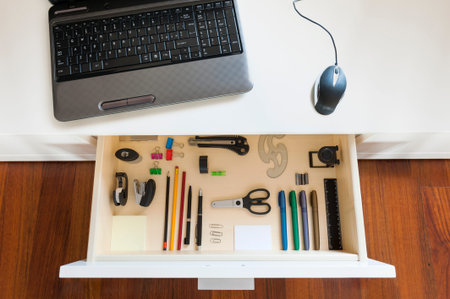 desk with notebook and open drawer with office toolsの写真素材
