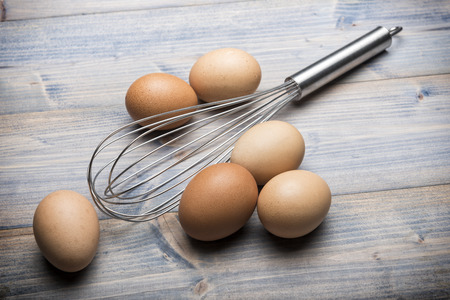 group of eggs with beater on wooden tableの写真素材