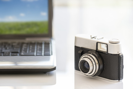 35mm vintage photocamera on white table near notebookの写真素材