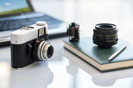 35mm vintage photocamera on table near lens, film and notebook