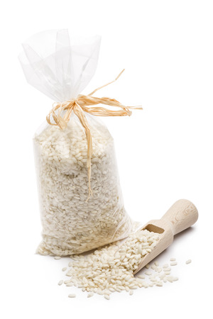 heap of white rice in transparent plastic bag with wooden scoop, on white background.の写真素材