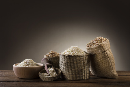 variety of different rice in rustic bowl and bags on wooden tableの写真素材