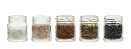 variety of natural and spicy salt into glass jars on white backgroundの写真素材