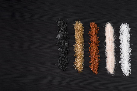 variety of natural and spicy salt on black table with copy spaceの写真素材