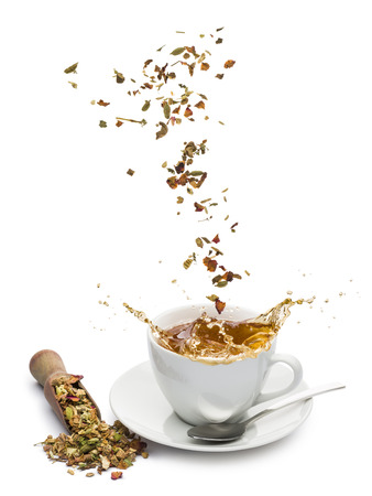 cup of tea with tea mixture falling and splashing on white backgroundの写真素材