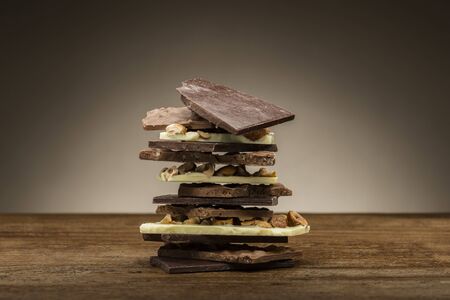 pile of mixed chocolate pieces, on wooden tableの写真素材