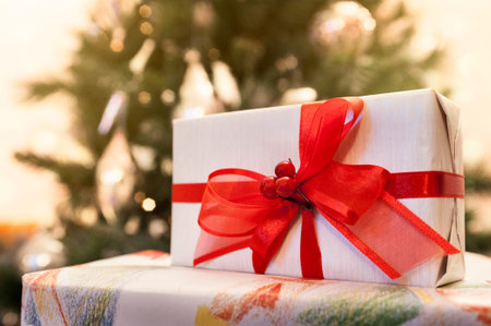 Decorated gift boxes with lighted christmas tree on background
