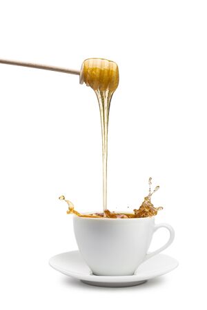 Honey dripping into cup of tea, on white backgroundの写真素材