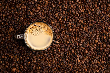 glass cup full of coffee over a background of coffee beansの写真素材