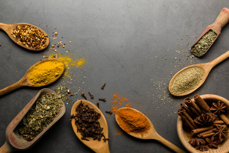 various spices on wooden spoons, on gray table with copy spaceの写真素材