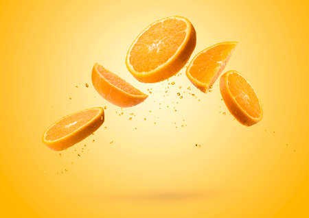 Orange fruit slices flying and dripping on colored backgroundの写真素材