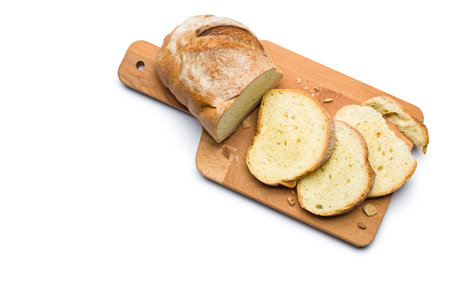 Sliced fresh bread and crumbs on wooden cutting board. Top view isolated on white background.