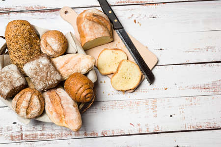 Assortment of baked bread into basket on wooden table. Top viewの写真素材