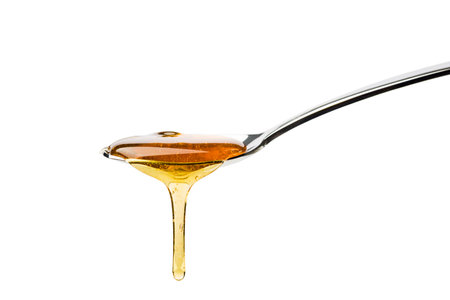 Honey dripping from spoon, isolated on white.の写真素材