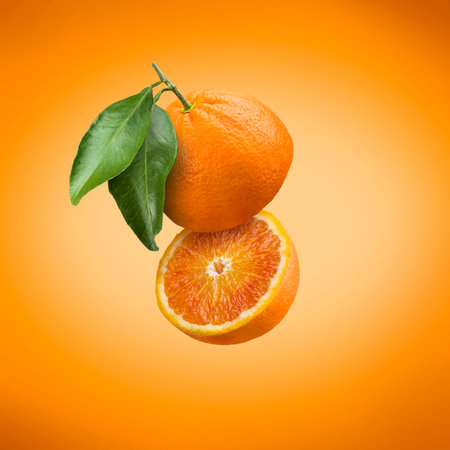 Sliced floating orange fruit with leaves on colorful background.の写真素材