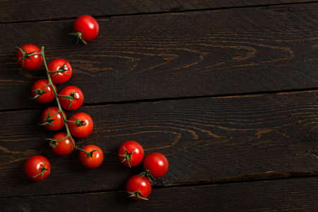 Small red cherry tomatoes on wooden table.の写真素材