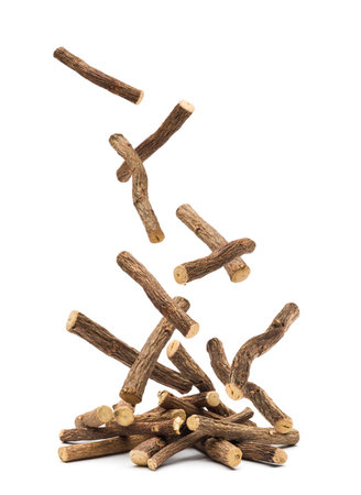 Sticks of liquorice root falling on white background.